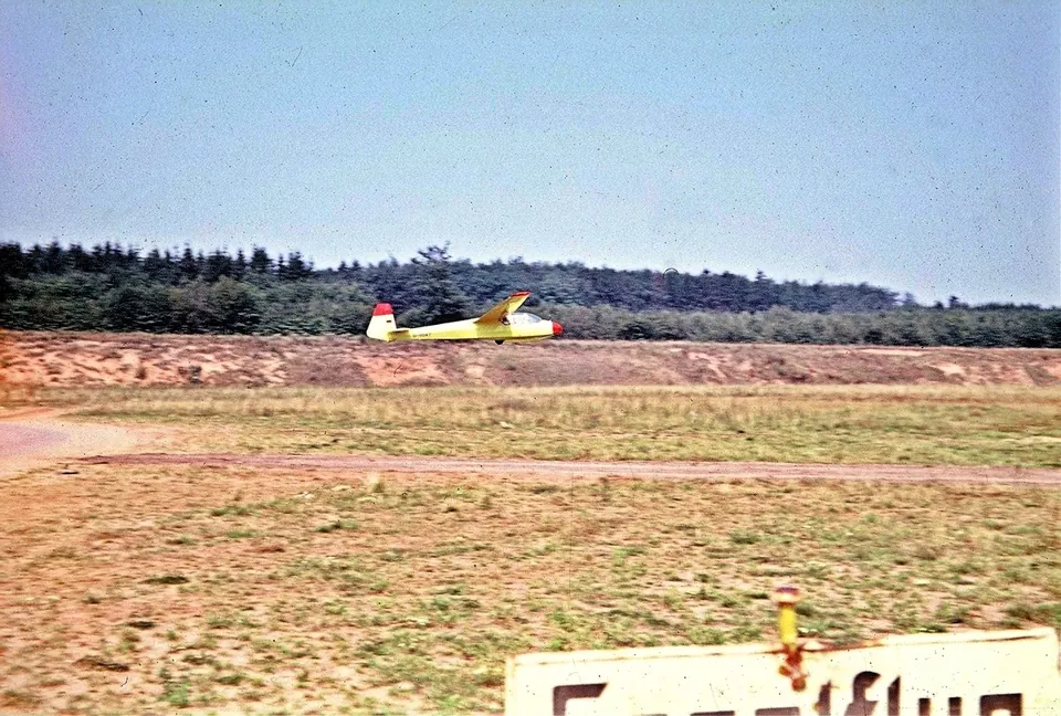 Segelfluggelände mit gelbem Segelflugzeug in weiter Landschaft
