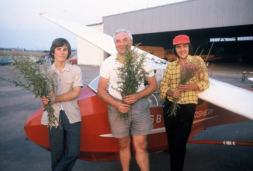 Drei Personen mit Blumensträußen vor einem Segelflugzeug