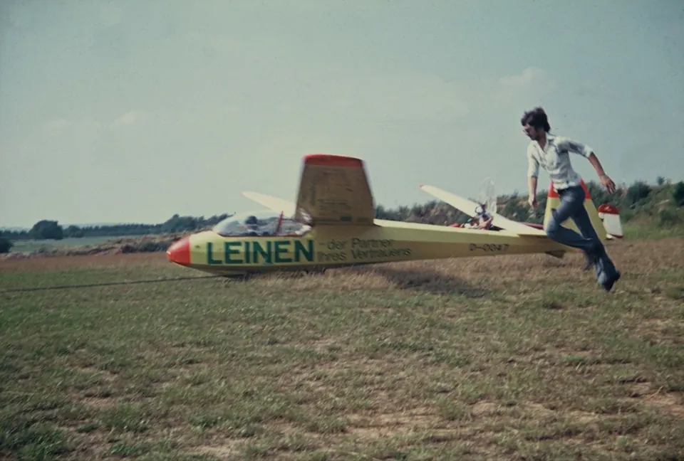 Segelflugzeug auf dem Gelände, ein Mann läuft zum Flugzeug