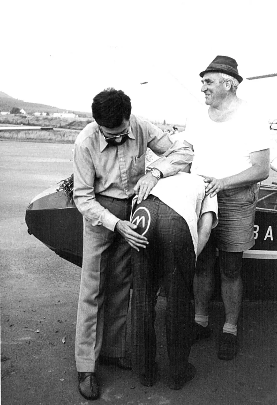 Historisches Schwarzweißfoto: zwei Männer am Flugzeug, einer mit Hut