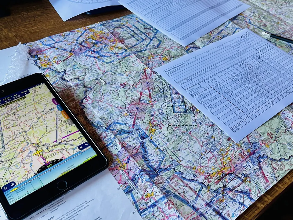 Luftfahrtkarte und Tablet mit Navigations-App auf dem Tisch zur Flugplanung