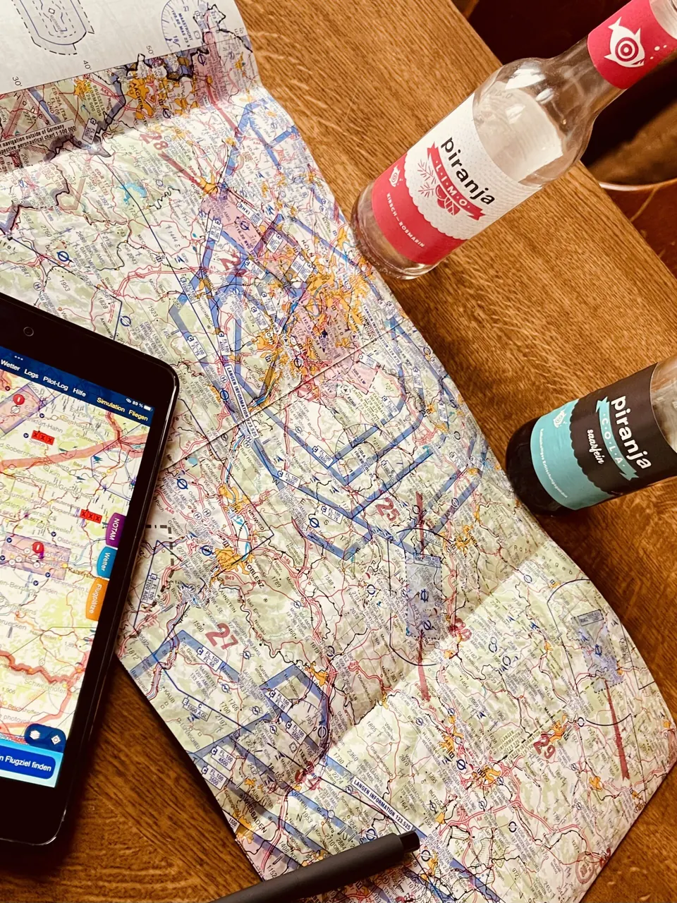 Luftfahrtkarte mit Navigations-Tablet auf einem Holztisch