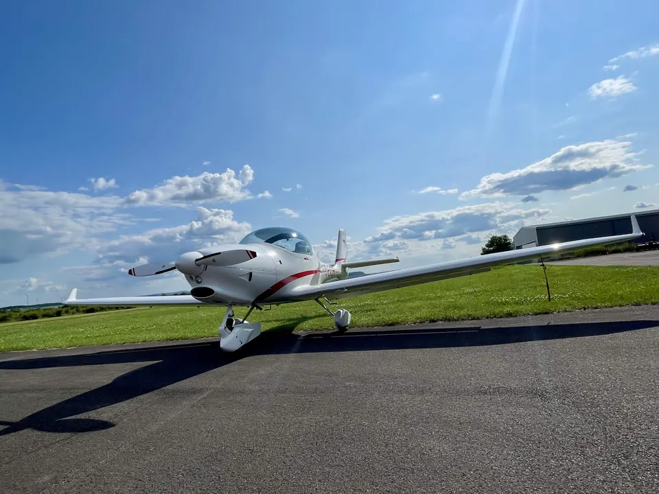 Aquila A210 auf der Piste vor grüner Wiese bei blauem Himmel