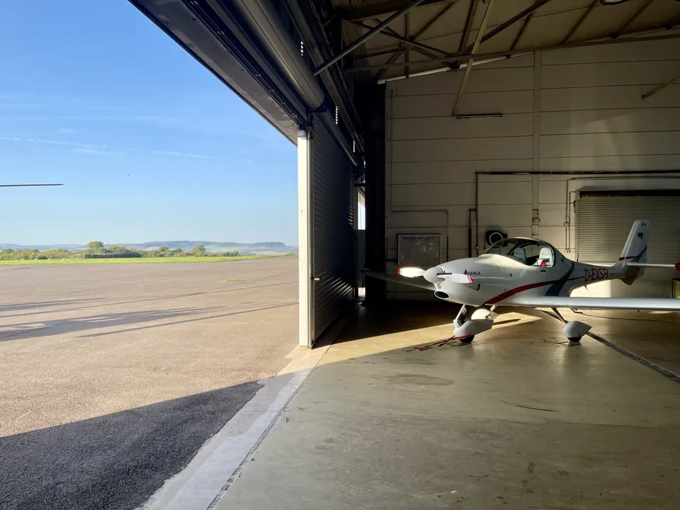 Aquila A210 im geöffneten Hangar am Flugplatz Saarlouis-Düren