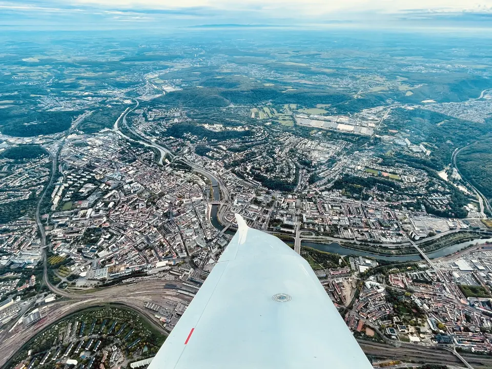Blick aus dem Cockpit auf die Tragfläche und die Stadt Saarlouis an der Saar aus der Luft