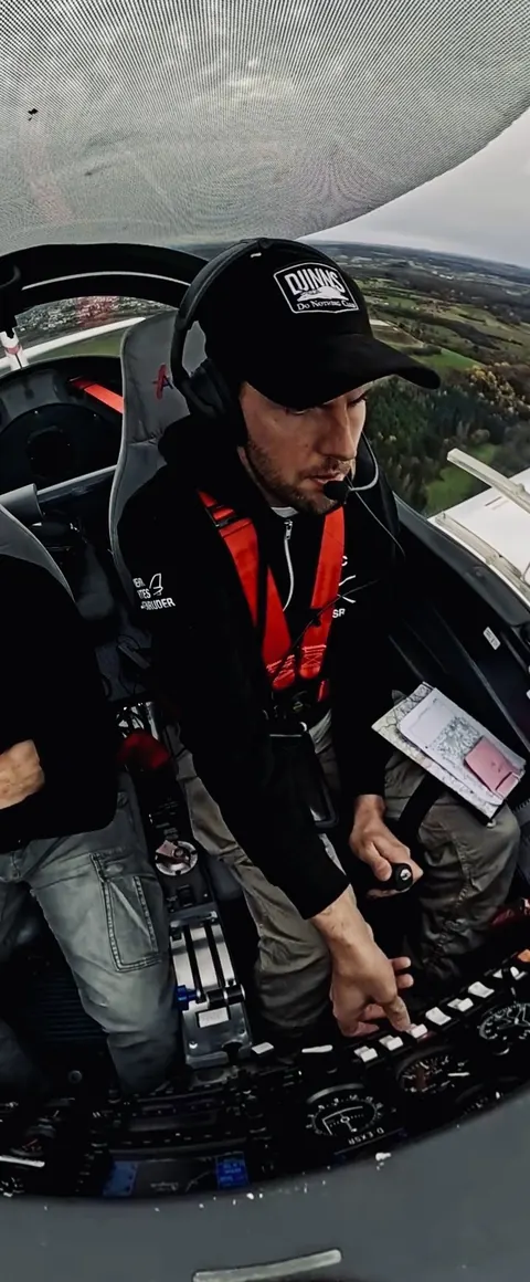 Flugschüler im Cockpit der Aquila mit Headset und Gurtzeug beim Flug über dem Saarland