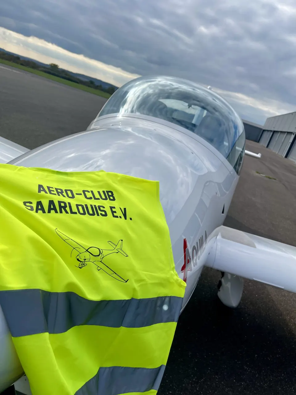 Gelbe Warnweste mit Aufdruck „Aero-Club Saarlouis e.V.“ über dem Flugzeug