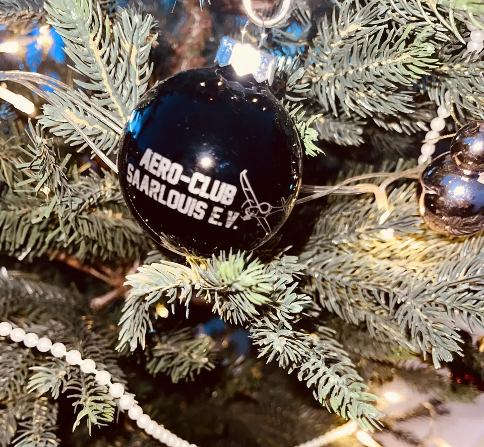 Schwarze Weihnachtskugel mit Logo des Aero-Club Saarlouis am Tannenzweig