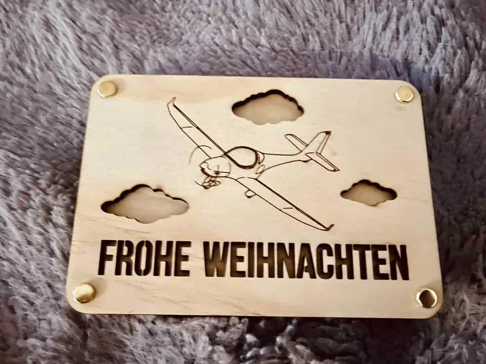 Weihnachtskarte aus Holz mit Flugzeug und Wolken, Aufschrift „Frohe Weihnachten“